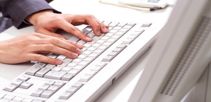 パソコンのキーボードとパソコンを打つ男性の手の画像