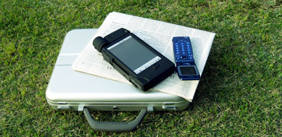 芝生の上にバックと新聞紙と携帯が置いてある画像